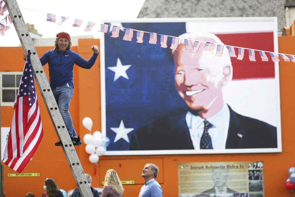 A man puts a U.S. flag up in the town of Ballina, the ancestral home of President elect Joe Biden, in North West of Ireland on Nov. 7, 2020. (AP Photo/Peter Morrison)