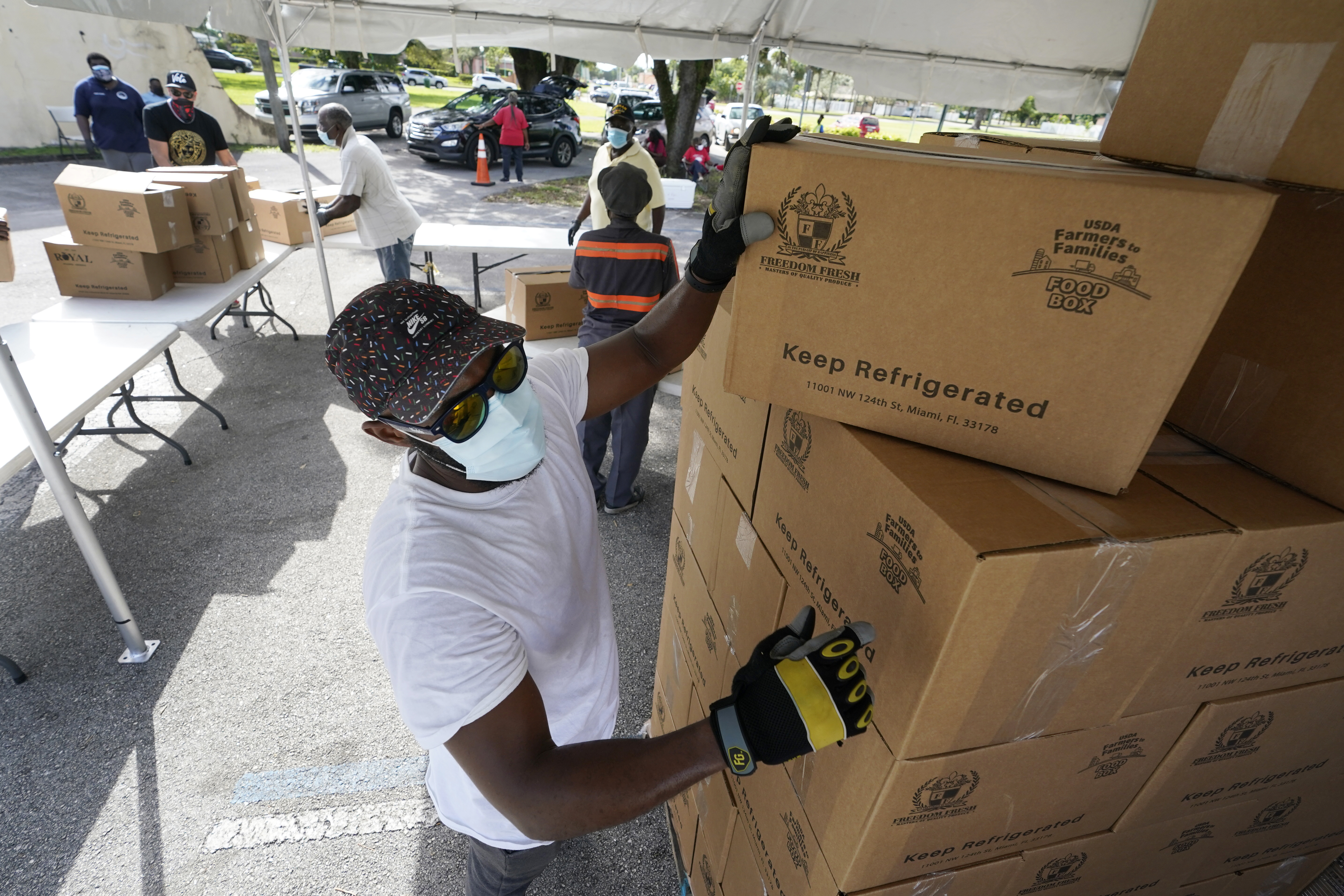 In this Oct. 6, 2020, file photo, city worker Randy Greice, foreground, unloads a pallet of food at a food distribution event in Opa-locka, Fla. President-elect Joe Biden will inherit a mangled U.S. economy, one that never fully healed from the coronavirus and could suffer again as new infections are climbing. The once robust recovery has shown signs of gasping after federal aid lapsed. Ten million remain jobless and more layoffs are becoming permanent. The Federal Reserve found that factory output dropped. (AP Photo/Wilfredo Lee, File)