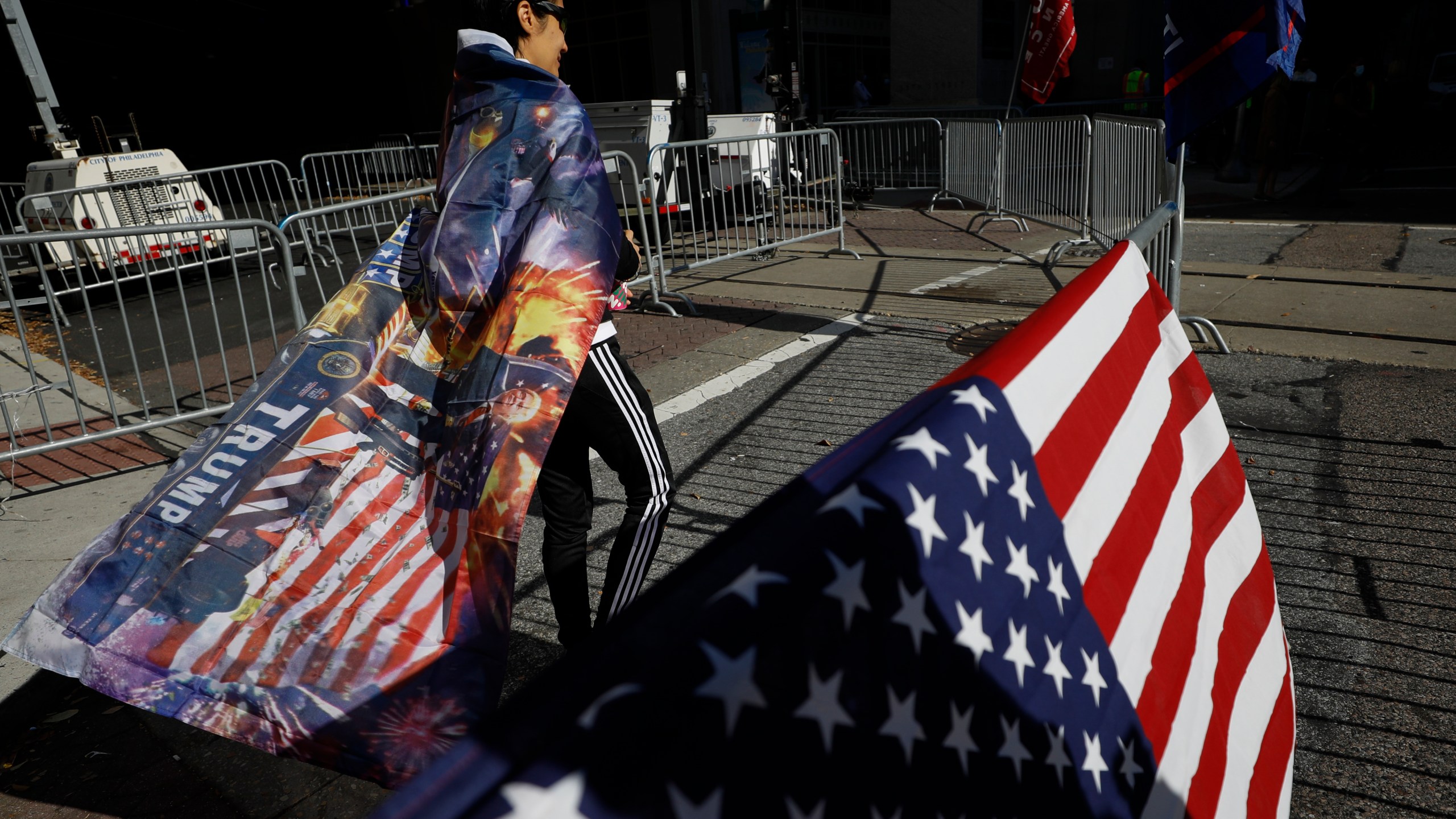 A woman wears a Trump flag as a cape as supporters of President Donald Trump protest outside the Pennsylvania Convention Center, where vote counting continues, in Philadelphia, on Nov. 9, 2020, two days after the 2020 election was called for Democrat Joe Biden. (Rebecca Blackwell / Associated Press)