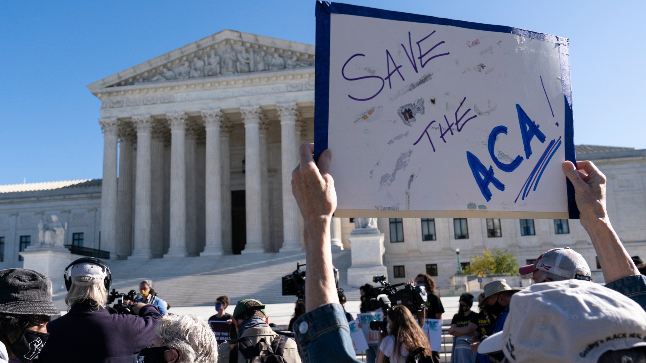 A demonstrator holds a sign in front of the U.S. Supreme Court as arguments are heard about the Affordable Care Act, Tuesday, Nov. 10, 2020, in Washington. (AP Photo/Alex Brandon)