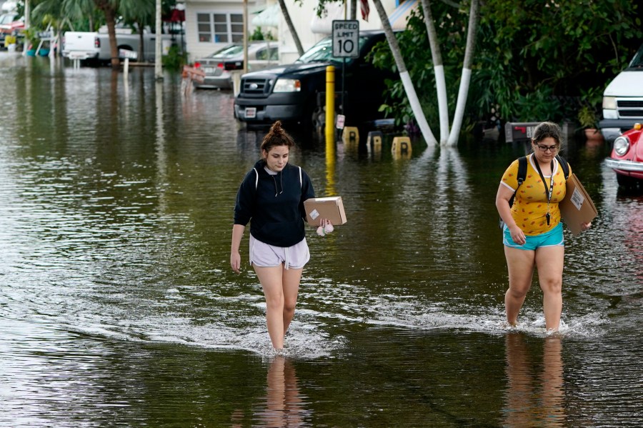 Victoria Rodriguez, left, and Angela Mojica, right, walk on a flooded street in the Driftwood Acres Mobile Home Park, in the aftermath of Tropical Storm Eta, Tuesday, Nov. 10, 2020, in Davie, Fla. (Lynne Sladky/AP Photo)