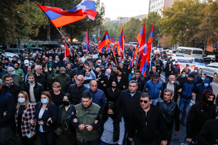 Protesters with Armenian flags walk along a street during a protest against an agreement to halt fighting over the Nagorno-Karabakh region, in Yerevan, Armenia on Nov. 12, 2020. (AP Photo/Dmitri Lovetsky)