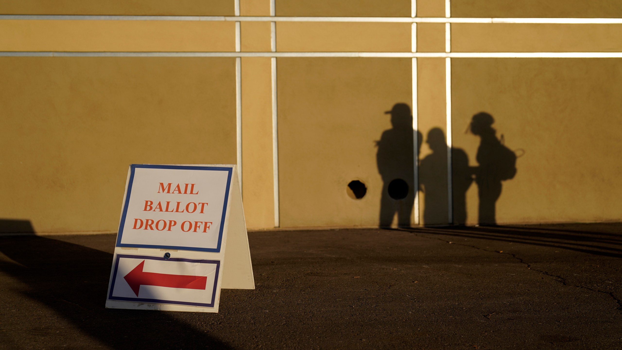 In this Nov. 3, 2020, file photo people wait outside of a polling place on Election Day in Las Vegas. Nevada election law stipulates that in order to register to vote, an individual must have been a resident for 30 days preceding an election, but does not specify how long an already registered voter must be physically present in the state in order to participate in an election. (AP Photo/John Locher, File)