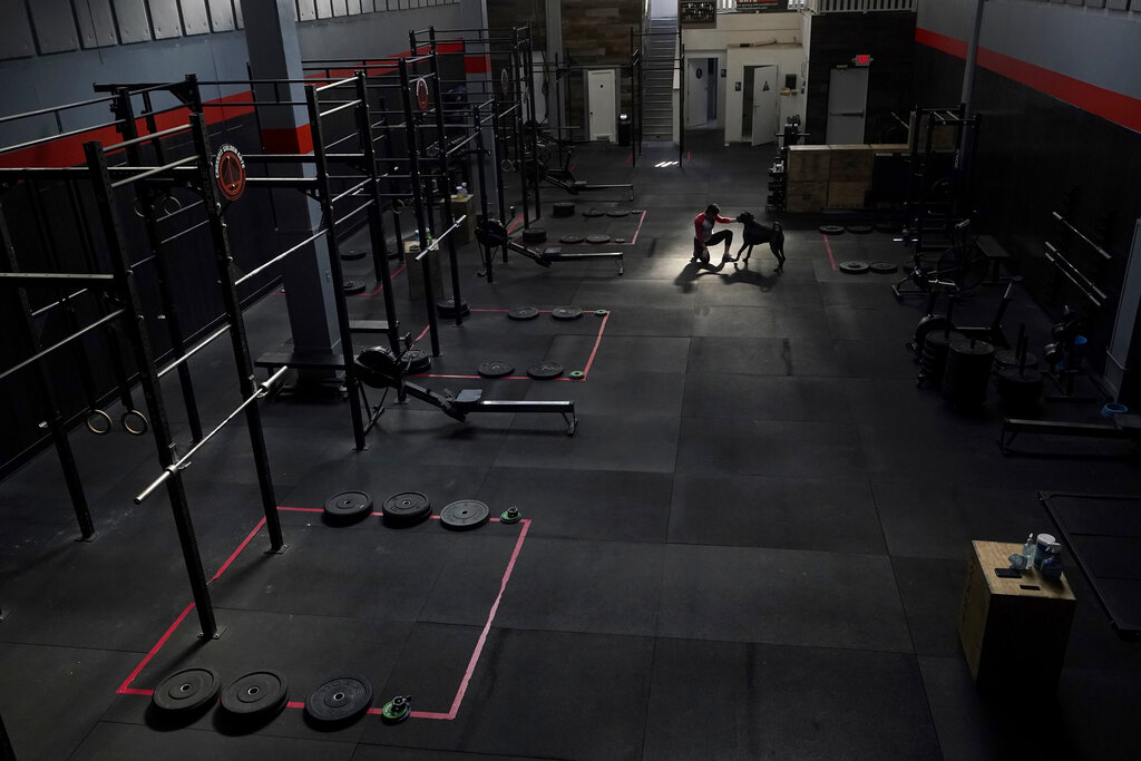 CrossFit Golden Gate owner Danielle Rabkin plays with her dog Bruno while interviewed at her gym in San Francisco on Nov. 12, 2020. (AP Photo/Jeff Chiu)