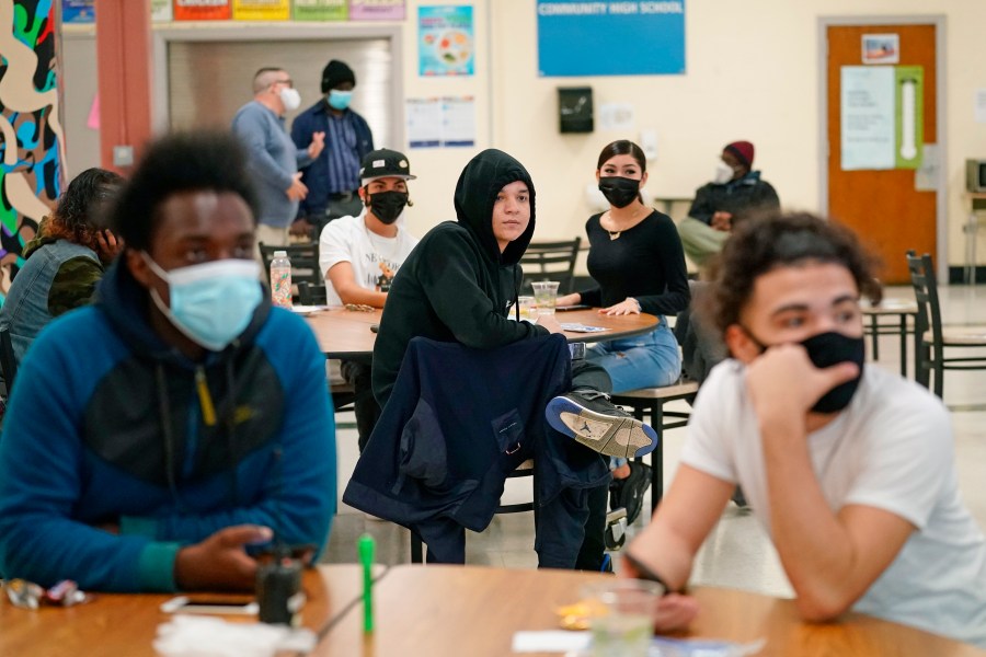 In this Oct. 29, 2020, file photo, students at West Brooklyn Community High School listen to questions posed by their principal during a current events-trivia quiz and pizza party in the school's cafeteria in New York. (AP Photo/Kathy Willen, File)