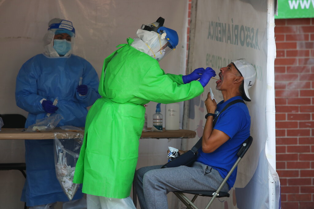 A healthcare worker tests a person for the new coronavirus inside a diagnostic tent in Mexico City, Saturday, Nov. 14, 2020. (AP Photo/Ginnette Riquelme)