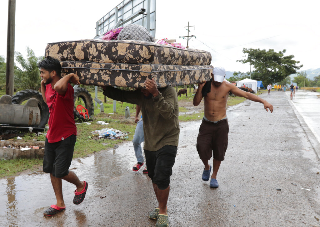 Neighbors help each other as they evacuate the area before Hurricane Iota makes landfall in San Manuel Cortes, Honduras, Monday, November 16, 2020. (AP Photo/Delmer Martinez)