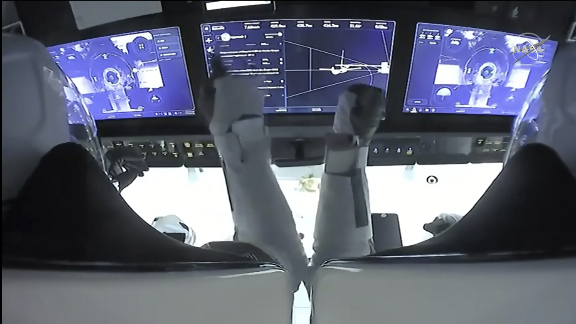 In this frame grab from NASA TV, astronauts Mike Hopkins, left, and Victor Glover monitor controls aboard SpaceX Dragon as the capsule approaches the International Space Station on Nov. 16, 2020. (NASA TV via Associated Press)