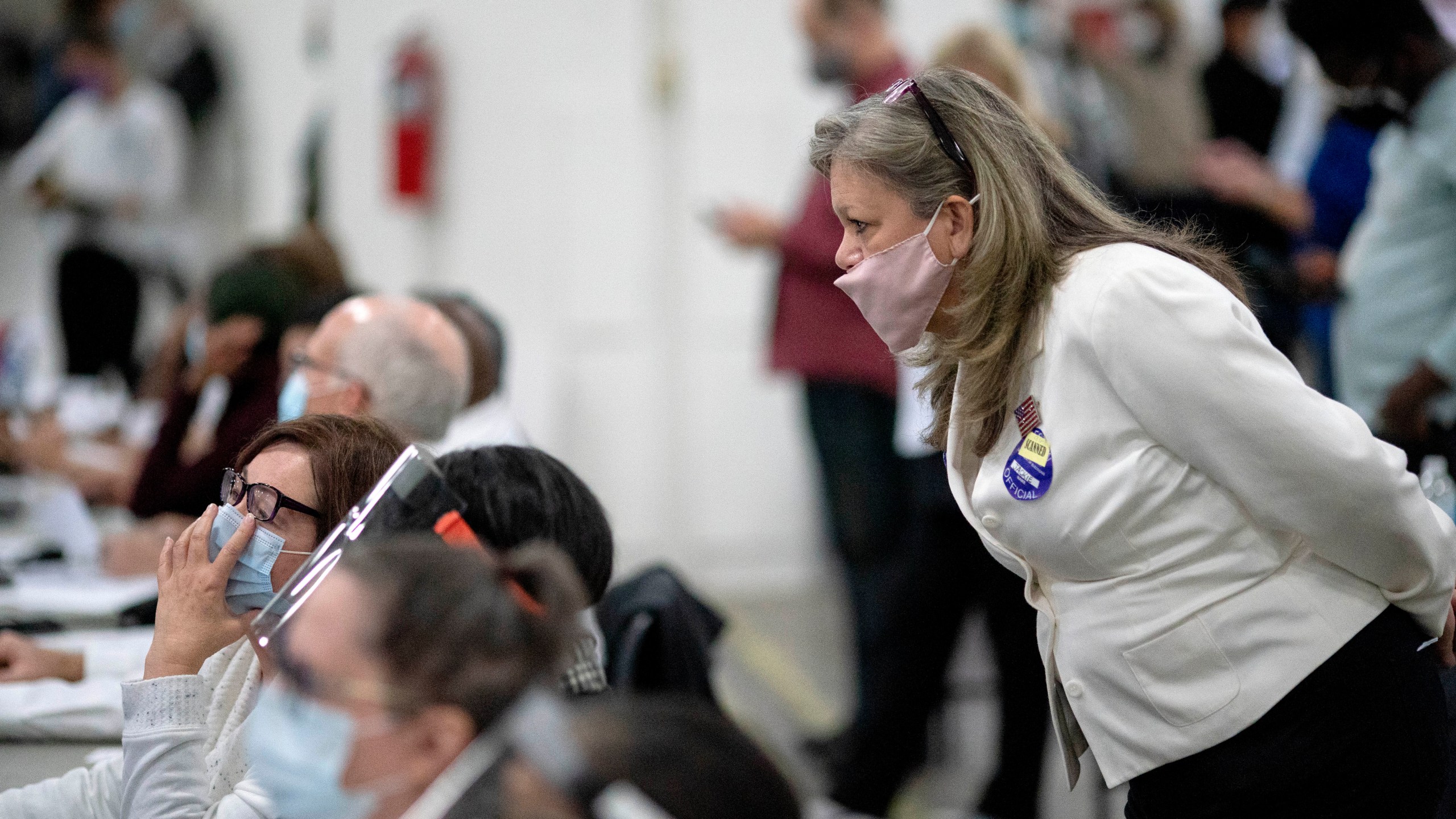 In this Nov. 4, 2020, file photo, a Republican election challenger at right watches over election inspectors as they examine a ballot as votes are counted into the early morning hours at the central counting board in Detroit. (AP Photo/David Goldman, File)