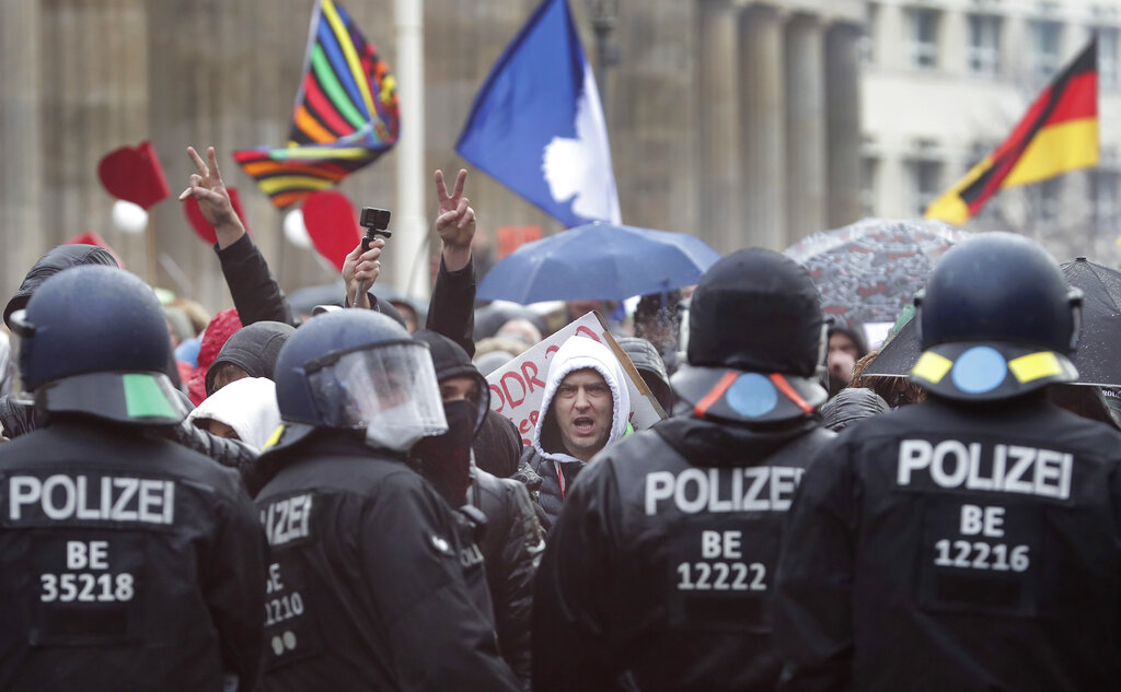 A protestor shouts as people attend a protest rally in front of the Brandenburg Gate in Berlin, Germany, Wednesday, Nov. 18, 2020 against the coronavirus restrictions in Germany. (AP Photo/Michael Sohn)