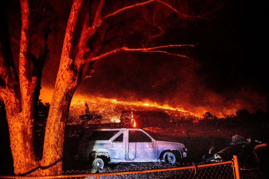 A scorched vehicle rests in a yard as the Mountain View Fire tears through the Walker community in Mono County, on Tuesday, Nov. 17, 2020. (AP Photo/Noah Berger)