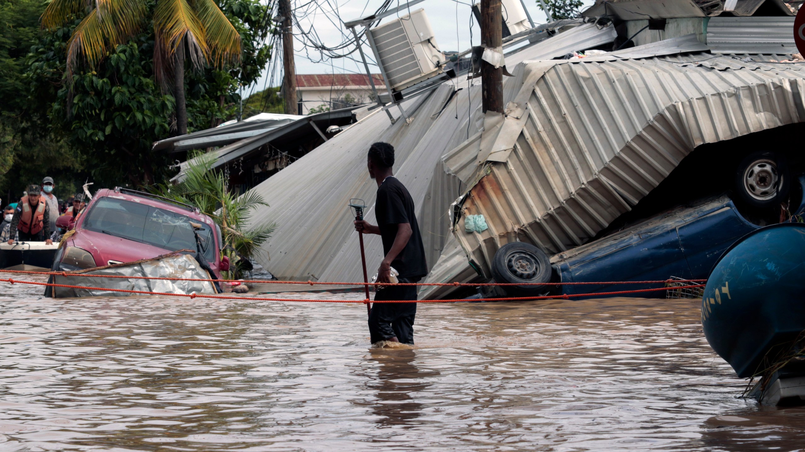 In this Nov. 6, 2020 file photo, a resident walking through a flooded street looks back at storm damage caused by Hurricane Eta in Planeta, Honduras. Flooded out Honduran and Guatemalan families stranded on rooftops in the most marginalized neighborhoods after the passage of hurricanes Eta and Iota portend a new wave of migration, observers across the region say. (AP Photo/Delmer Martinez, File)