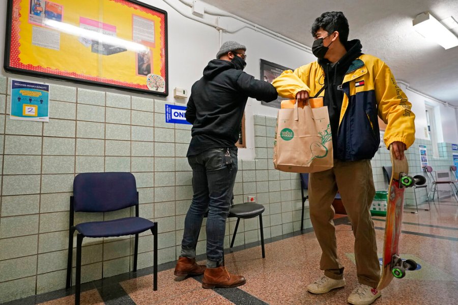 West Brooklyn Community High School principal Malik Lewis, left, bumps elbows with former student Jason Cardoso after Cardoso came to pick up the diploma he earned when he graduated in March, Thursday, Nov. 19, 2020, in the Brooklyn borough of New York. (AP Photo/Kathy Willens)