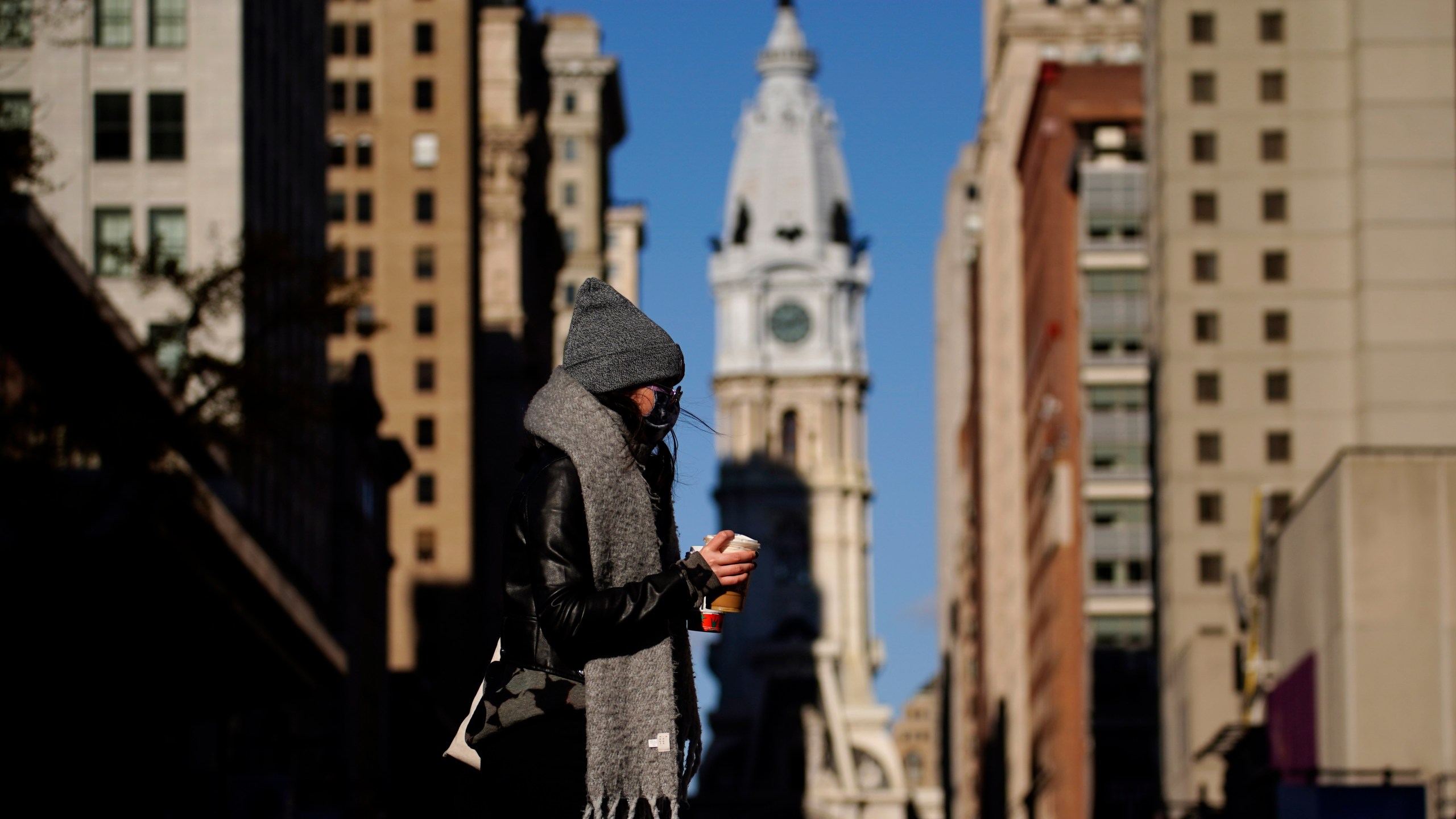 In this Nov. 18, 2020, photo, a person wearing a face mask crosses Broad Street in Philadelphia. (AP Photo/Matt Slocum)