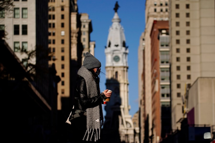 In this Nov. 18, 2020, photo, a person wearing a face mask crosses Broad Street in Philadelphia. (AP Photo/Matt Slocum)