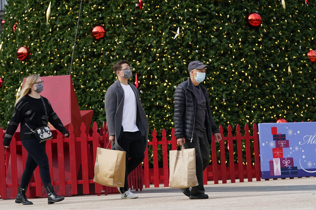 People carry shopping bags while walking past the annual Macy's Great Tree at Union Square during the coronavirus outbreak in San Francisco on Nov. 21, 2020. (AP Photo/Jeff Chiu)