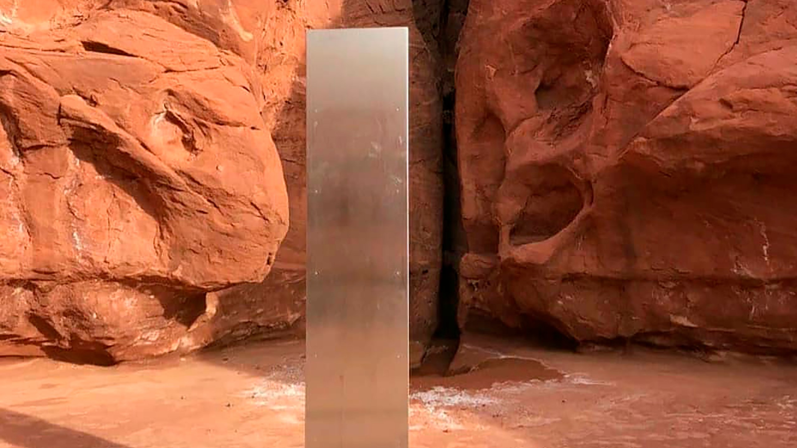 This Nov. 18, 2020 photo provided by the Utah Department of Public Safety shows a metal monolith installed in the ground in a remote area of red rock in Utah. The smooth, tall structure was found during a helicopter survey of bighorn sheep in southeastern Utah, officials said Monday. State workers from the Utah Department of Public Safety and Division of Wildlife Resources spotted the gleaming object from the air and landed nearby to check it out. The exact location is so remote that officials are not revealing it publicly, worried that people might get lost or stranded trying to find it and need to be rescued. (Utah Department of Public Safety via AP)