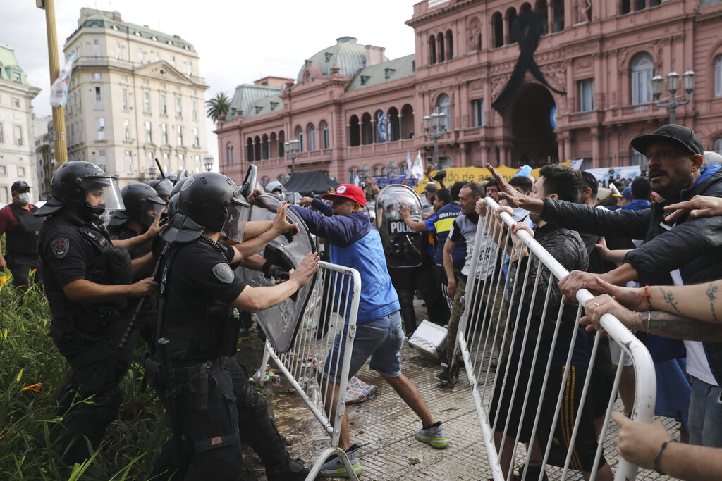 Soccer fans waiting to see Diego Maradona lying in state clash with police outside the presidential palace in Buenos Aires, Argentina, Thursday, Nov. 26, 2020. (AP Photo/Rodrigo Abd)