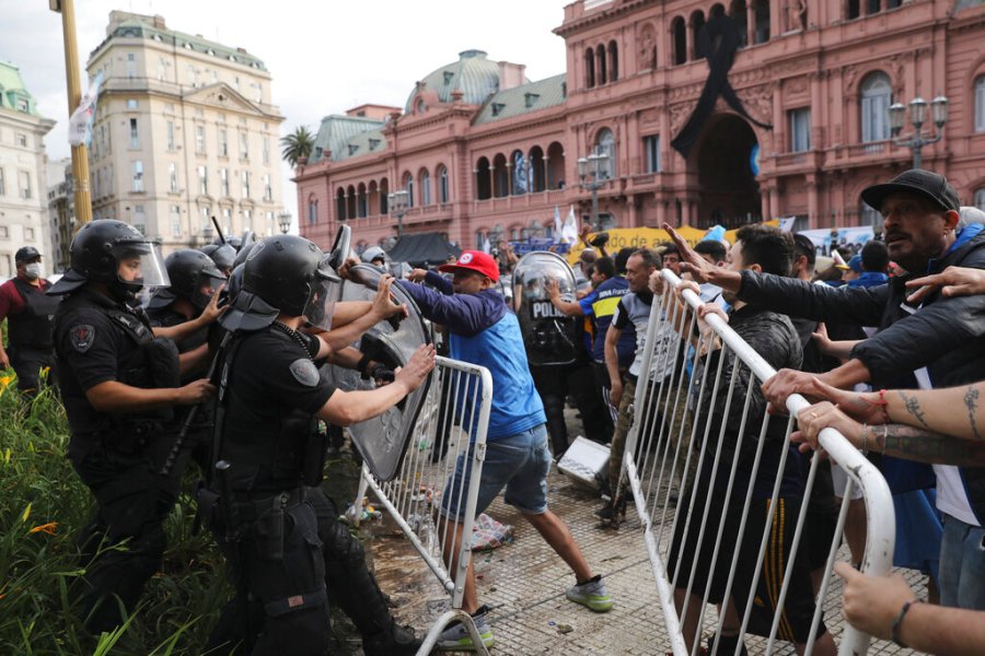 Soccer fans waiting to see Diego Maradona lying in state clash with police outside the presidential palace in Buenos Aires, Argentina, Thursday, Nov. 26, 2020. (AP Photo/Rodrigo Abd)