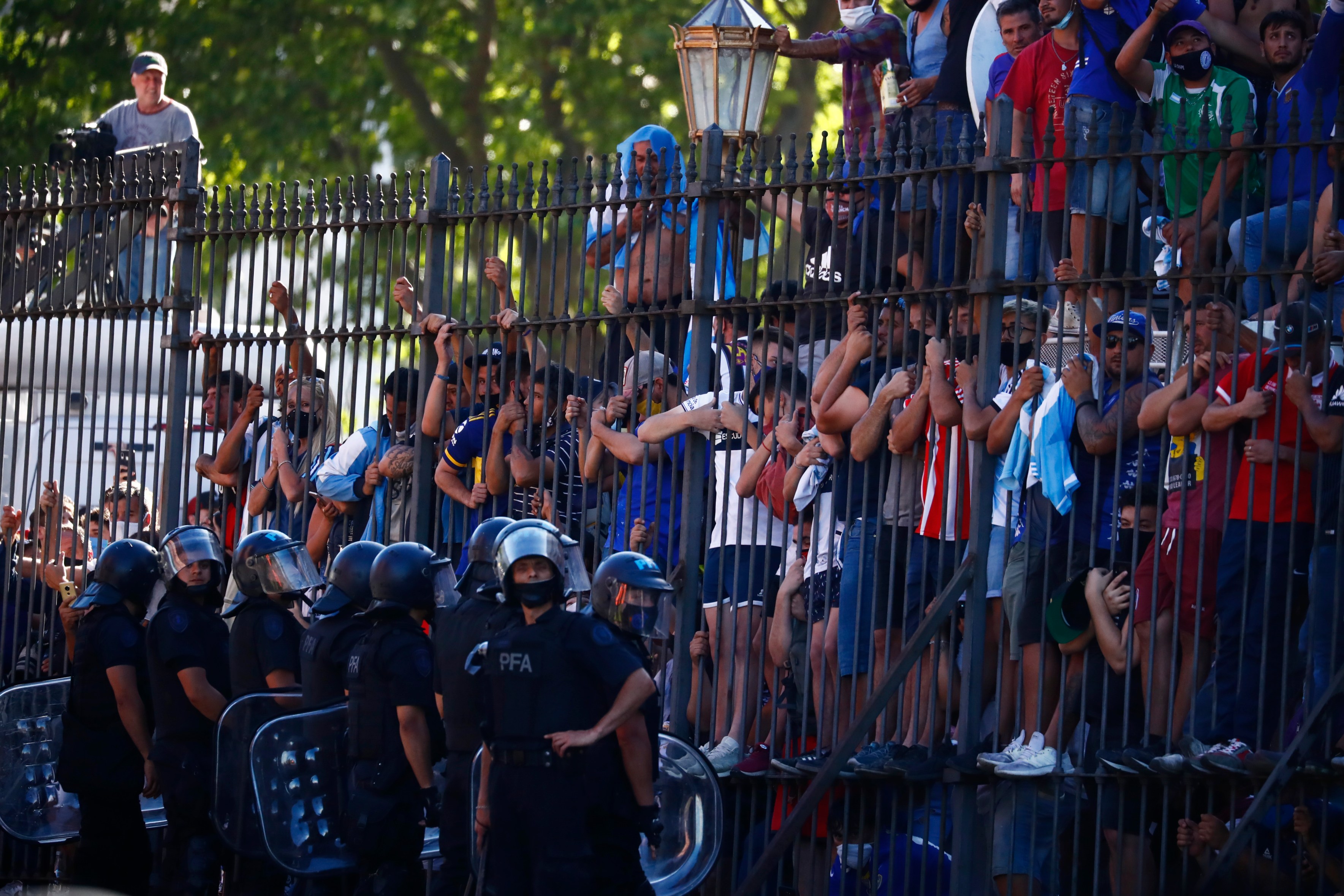 Mourning fans climb the fence of the presidential palace to get a glimpse of the casket carrying Diego Maradona's body in Buenos Aires, Argentina, on Nov. 26, 2020. (Marcos Brindicci / Associated Press)