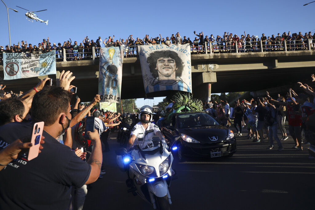 Mourning fans wave from an overpass at the caravan carrying the remains of Diego Maradona to his resting place in Buenos Aires, Argentina, Thursday, Nov. 26, 2020. (AP Photo/Rodrigo Abd)