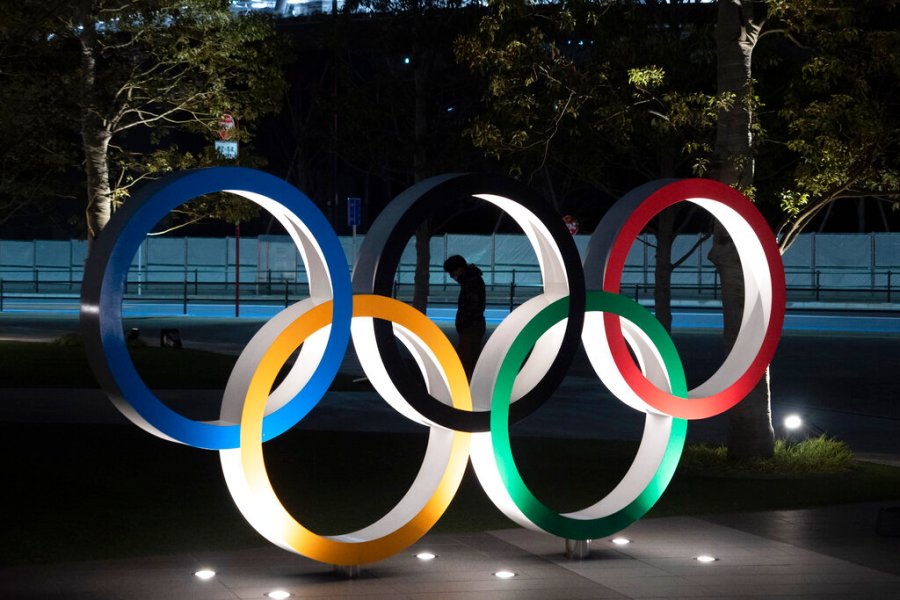 In this March 24, 2020, file photo, a man is seen through the Olympic rings in front of the New National Stadium in Tokyo.