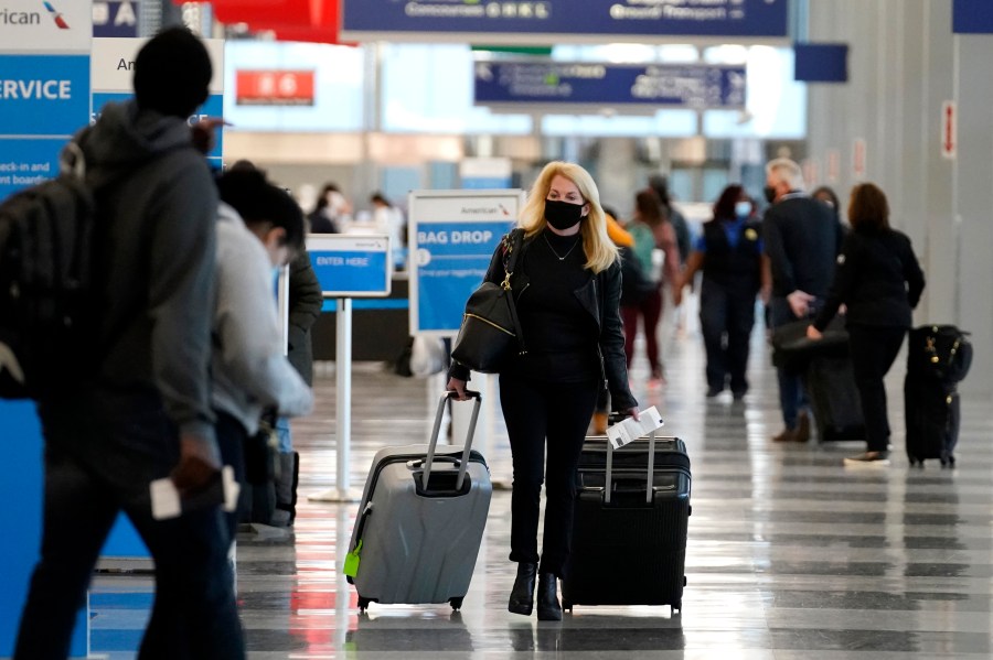 In this Sunday, Nov. 29, 2020 file photo, a traveler wears a mask as she walks through Terminal 3 at O'Hare International Airport in Chicago. (AP Photo/Nam Y. Huh, File)