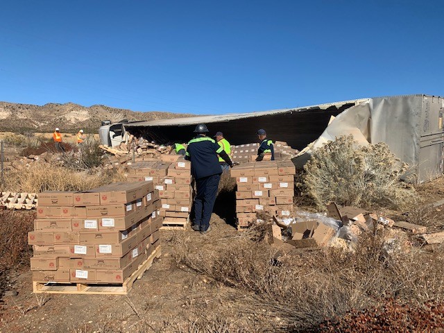 Caltrans crews help clean up the dozens of boxes of cookie dough alongside the Cajon Pass on Thursday. (Caltrans via Twitter)