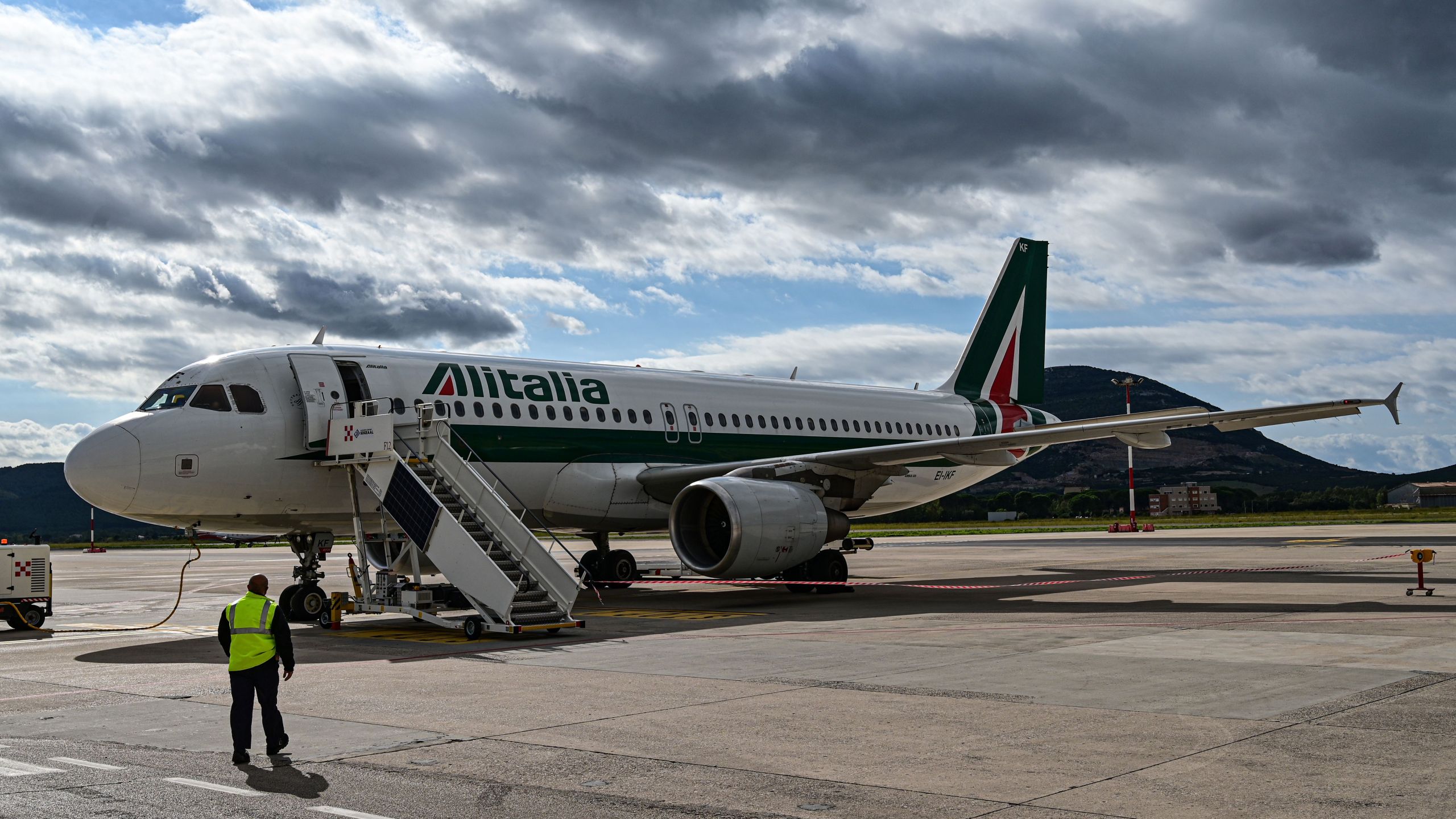 An airport employee walks towards an Alitalia plane just arrived at the Alghero-Fertilia "Riviera del Corallo" Airport on October 6, 2020. (Miguel Medina/AFP via Getty Images)