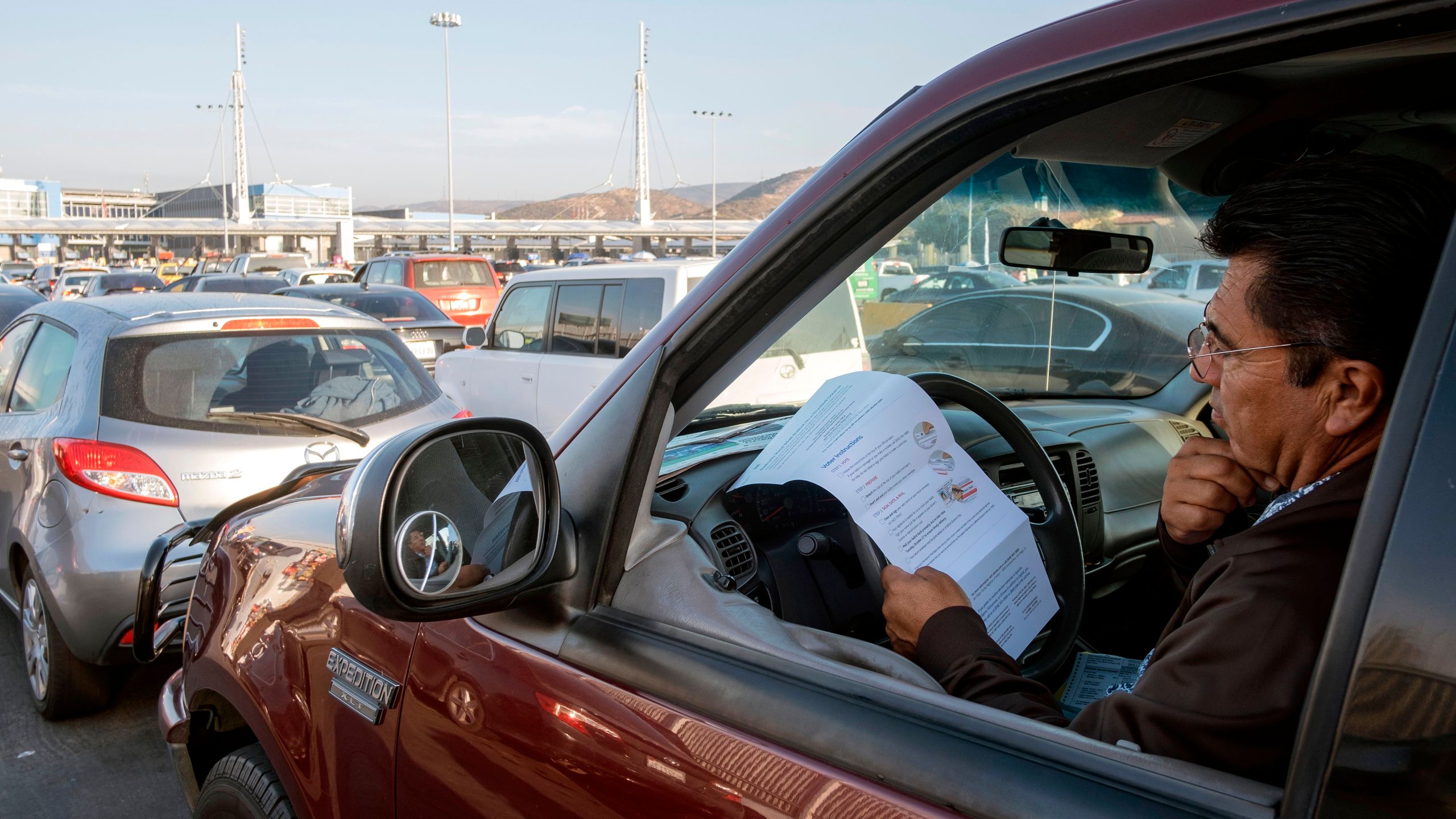 U.S. citizen Rafael Millan reads ballot instructions before crossing the border to deposit his vote, at the U.S.-Mexico border in San Ysidro Crossing Port in Tijuana on Nov. 3, 2020 (Guillermo Arias/AFP via Getty Images)