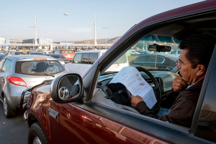 U.S. citizen Rafael Millan reads ballot instructions before crossing the border to deposit his vote, at the U.S.-Mexico border in San Ysidro Crossing Port in Tijuana on Nov. 3, 2020 (Guillermo Arias/AFP via Getty Images)