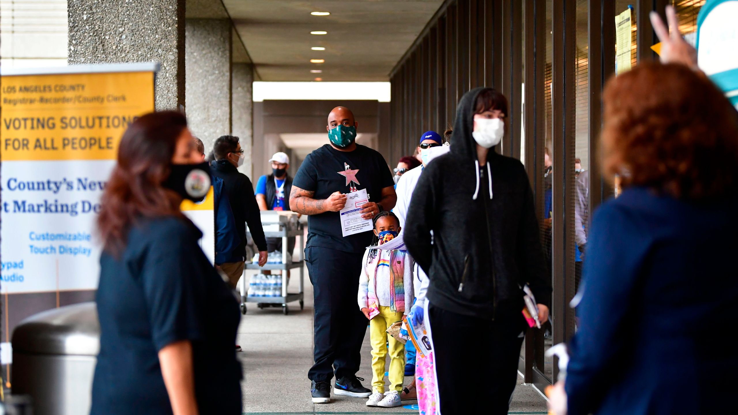 Voters wear face-coverings while waiting in line to vote for the 2020 US elections at the Los Angeles County Registrar in Norwalk on Nov. 3, 2020. (Frederic J. Brown / AFP / Getty Images)