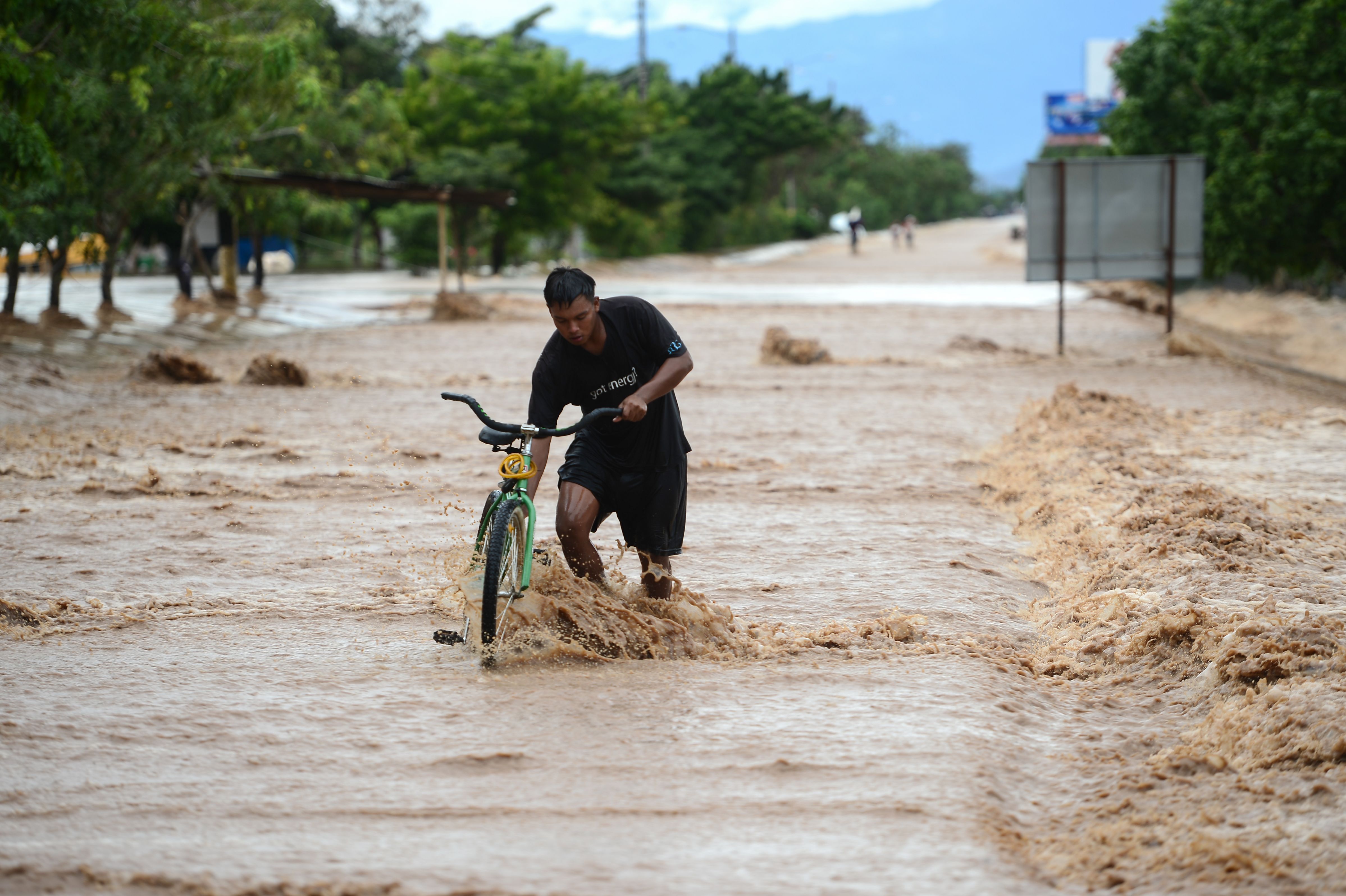 A man wades with his bike in a flooded street due to the heavy rains caused by Hurricane Eta, now degraded to a tropical storm, in El Progreso, department of Yoro, 260 kms north of Tegucigalpa, on Nov. 5, 2020. (Orlando SIERRA / AFP via Getty Images)