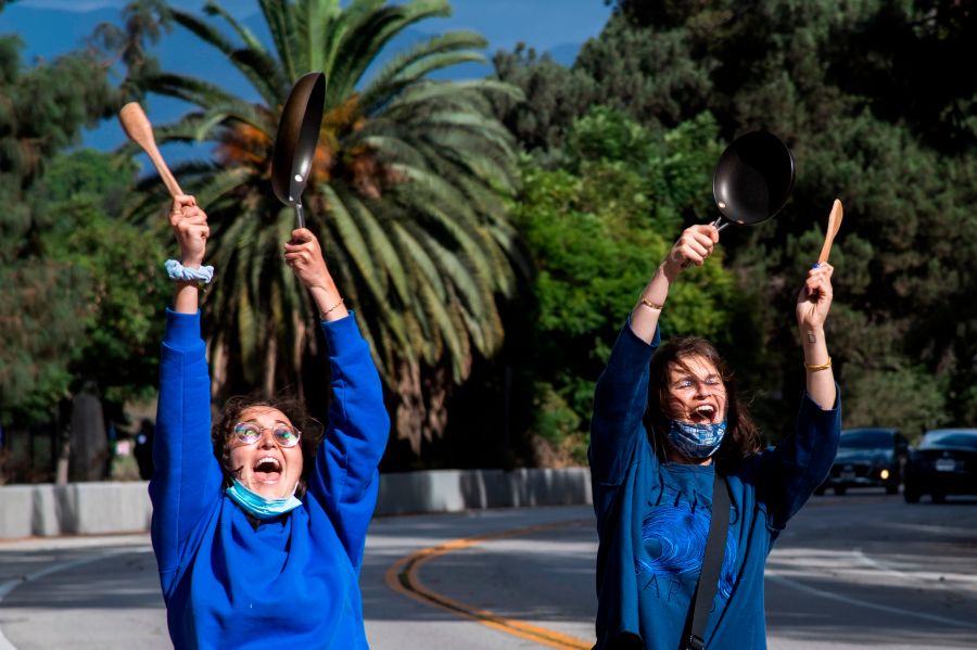 Los Angeles residents Emma Silvers and Hadley Rosenbaum bang pans as they run around the Silverlake reservoir to celebrate Joe Biden being declared the next U.S. President on Nov. 7, 2020. (ROBYN BECK/AFP via Getty Images)