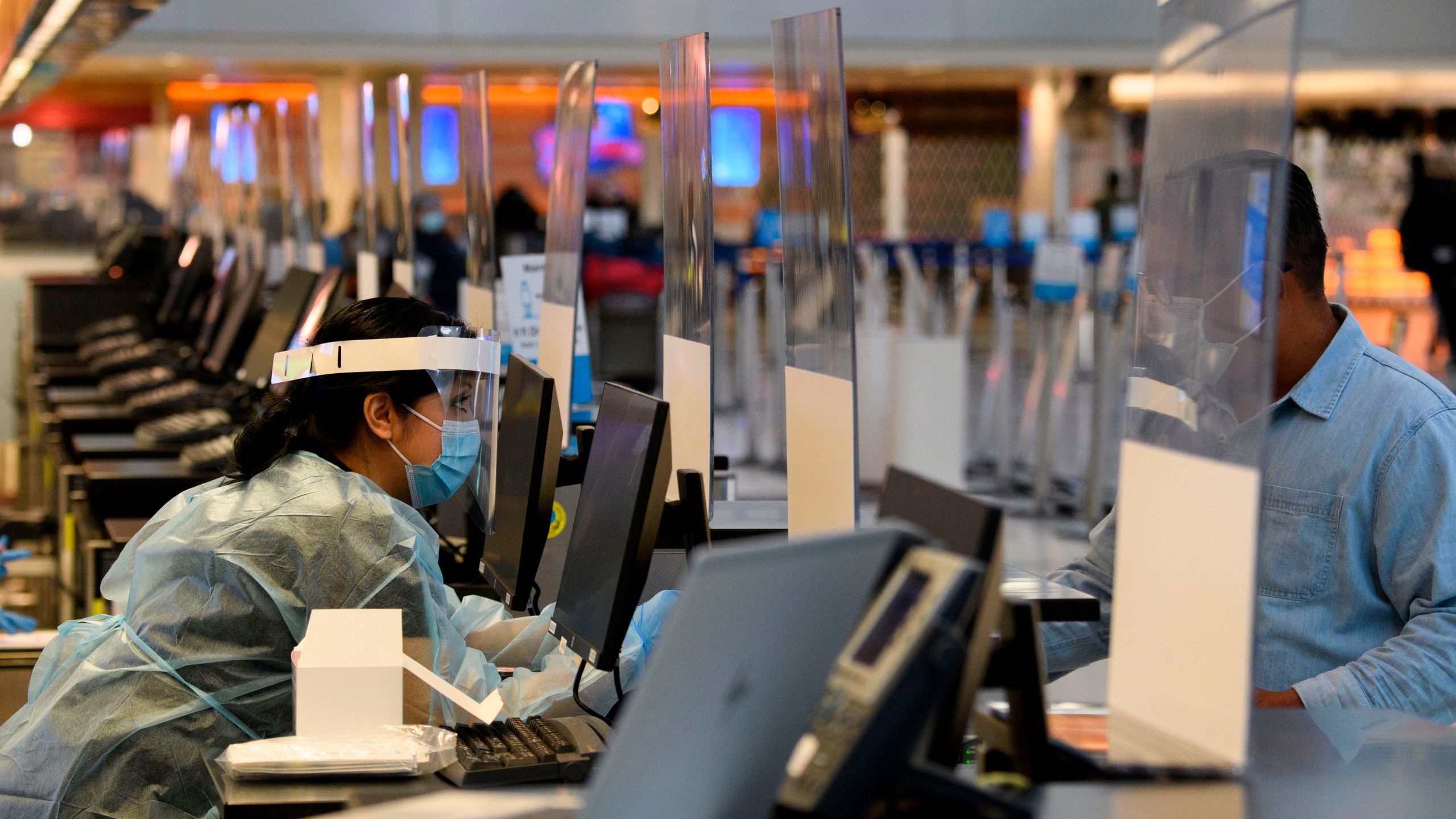 A staff member wears personal protective equipment while talking with a traveler at an coronavirus testing location at the Tom Bradley International Terminal at LAX on Nov. 18, 2020.(Patrick FALLON/AFP via Getty Images)