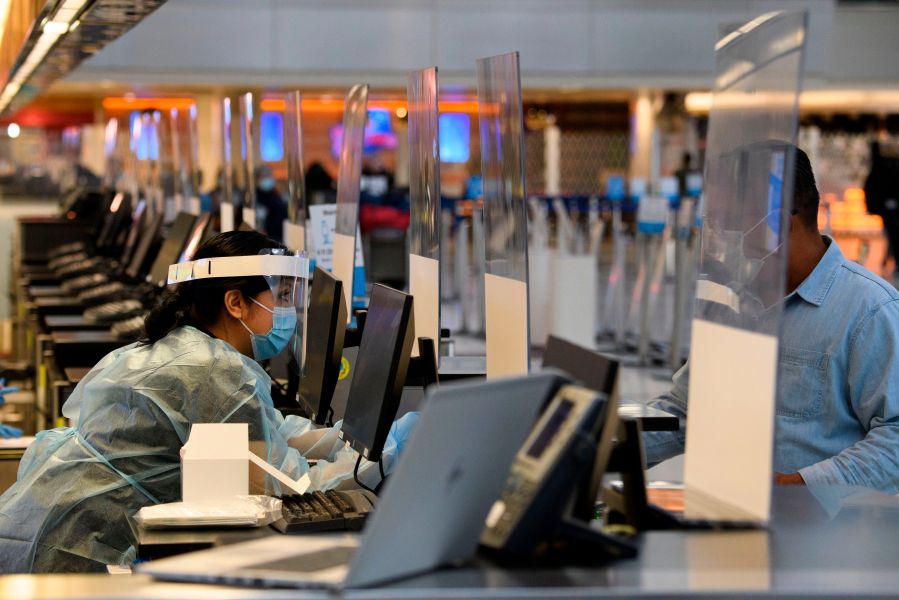 A staff member wears personal protective equipment while talking with a traveler at an coronavirus testing location at the Tom Bradley International Terminal at LAX on Nov. 18, 2020.(Patrick FALLON/AFP via Getty Images)