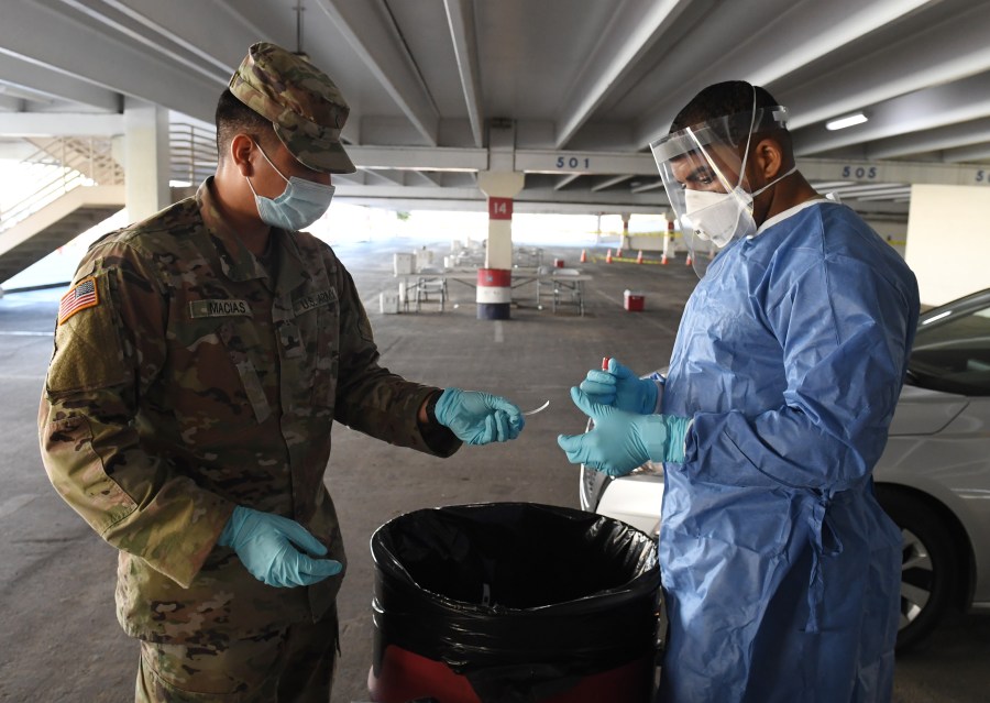 Spc. Jonathan Macias (L) and Spc. Demetrie Barnett of the Nevada National Guard prepare a coronavirus specimen sampling tube after administering a test during a preview of a free drive-thru testing site in the parking garage of the Texas Station Gambling Hall & Hotel on Nov. 12, 2020 in North Las Vegas, Nevada. (Ethan Miller/Getty Images)