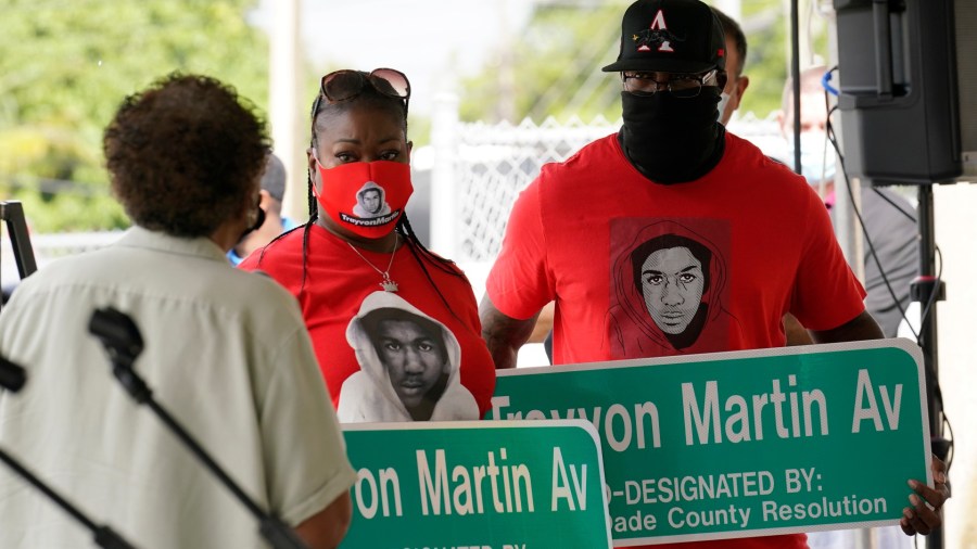 Sybrina Fulton, center and Tracy Martin, parents of Trayvon Martin, hold street signs with their son's name, Thursday, Nov. 5, 2020, in Miami Gardens, Fla. The street on the way to Martin's former school was renamed in his honor, eight years after he was killed by a neighborhood watch volunteer in Sanford, Fla. (AP Photo/Marta Lavandier)