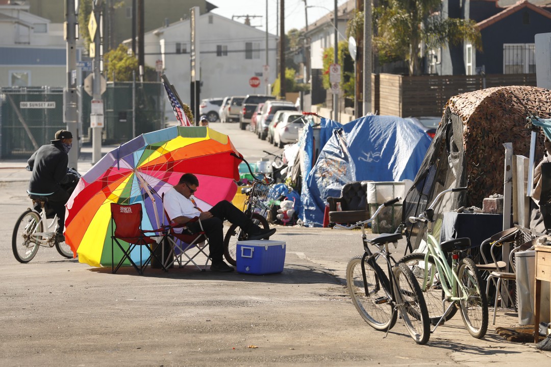 Richard Thompson seeks the shade of his umbrella as he is camped out with several others in a Venice parking lot across the street from one of 20 homeless shelters that have been established by Mayor Garcetti.(Al Seib/Los Angeles Times)