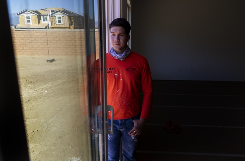 Vincent Aguayo, a first-year student at Cal State Sacramento, is shown at a new housing development in Riverside in 2020. He works a part-time job putting up drywall. (Gina Ferazzi / Los Angeles Times)