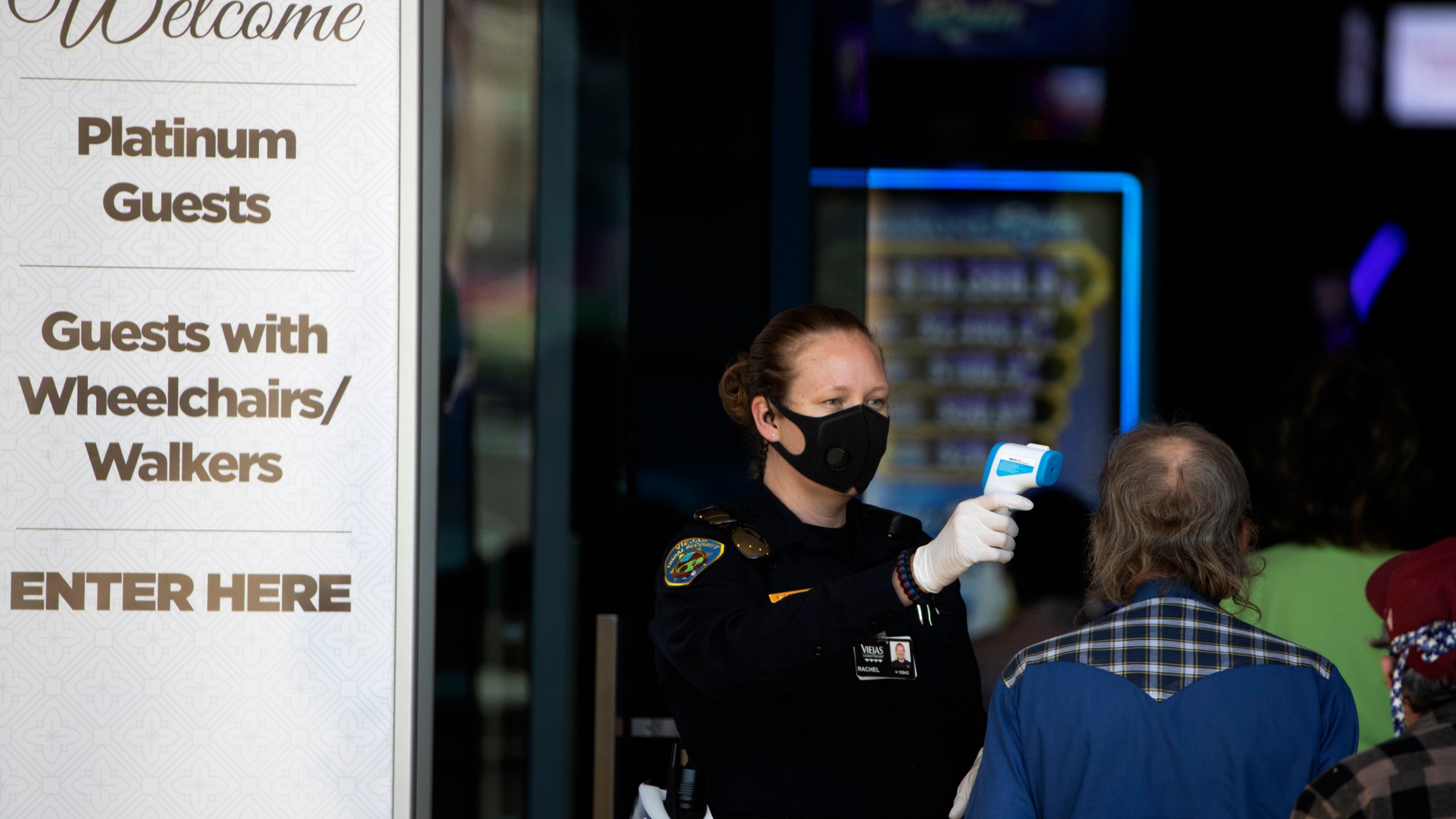 A security official checks the temperature of a man at the entrance to the Viejas Casino and Resort in Alpine, San Diego County, as it reopens on May 18, 2020. (Gregory Bull / Associated Press)