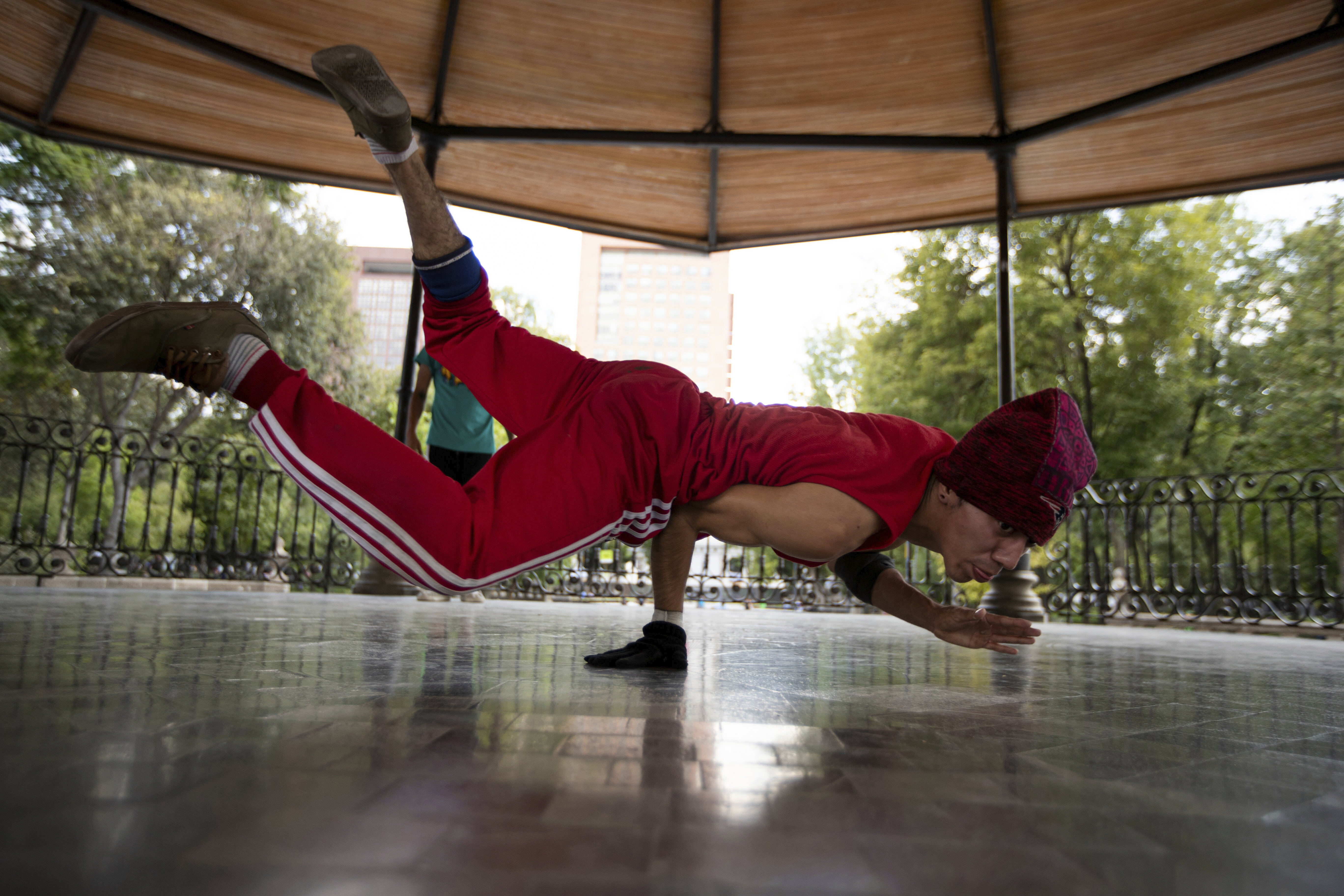 Carlos Cruz, a breakdancer, practices at a kiosk in Alameda park after being closed off to the public for nearly five months due to the new coronavirus pandemic, in Mexico City, Tuesday, Aug. 18, 2020. (AP Photo/Fernando Llano)