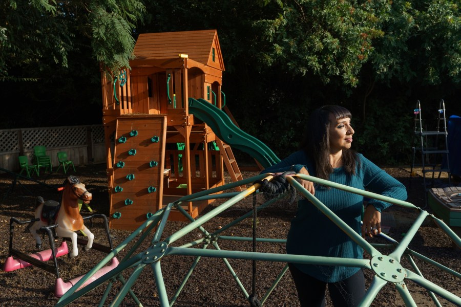 Mary De La Rosa stands inside a play structure in her home backyard, that once housed the now-closed child care program, Creative Explorers, Wednesday, Oct. 21, 2020, in Los Angeles. When De La Rosa closed her toddler and preschool program in March because of the coronavirus pandemic, she fully expected to serve the children again some day. In the end, though, Creative Explorers closed for good. The story of De La Rosa’s program is being repeated across the country as the pandemic’s effects ripple through child care, disproportionately affecting Black and Latino-owned centers in an industry that has long relied on providers of color. (AP Photo/Damian Dovarganes)