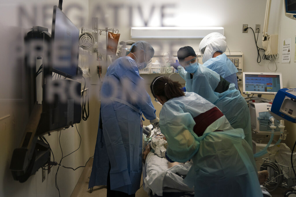 In this Nov. 19, 2020, file photo, EMT Giselle Dorgalli, second from right, looks at a monitor while performing chest compression on a patient who tested positive for coronavirus in the emergency room at Providence Holy Cross Medical Center in the Mission Hills section of Los Angeles. (AP Photo/Jae C. Hong, File)