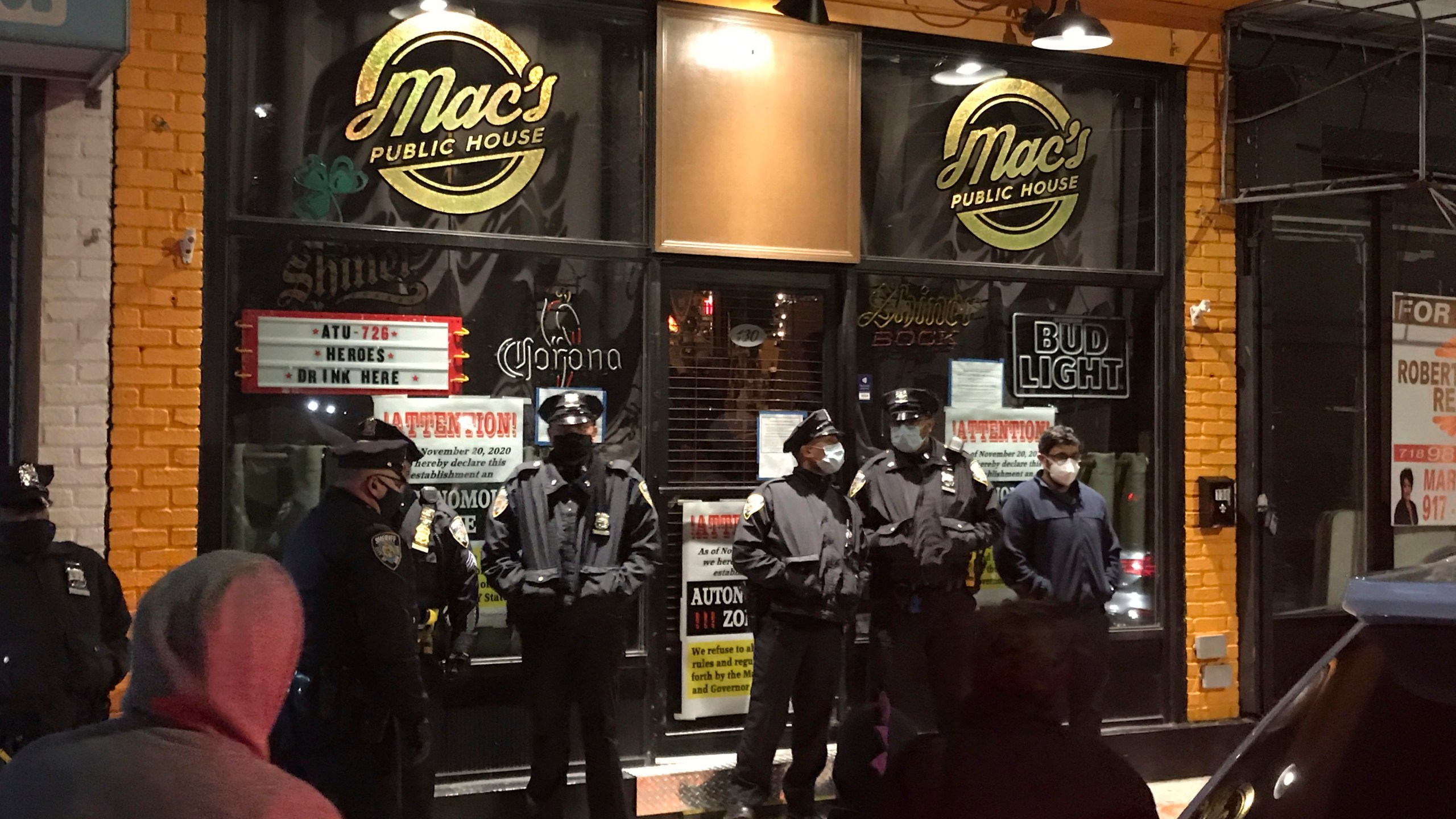 Officers from the New York City sheriff's office stand outside Mac's Public House on Tuesday, Dec. 1, 2020, on Staten Island, N.Y. An owner of the New York City bar that was providing indoor service in defiance of coronavirus restrictions was arrested after a sting in which plainclothes officers went inside and ordered food and beverages, the city sheriff's office said. (Irene Spezzamonte/Staten Island Advance via AP)