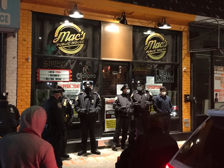 Officers from the New York City sheriff's office stand outside Mac's Public House on Tuesday, Dec. 1, 2020, on Staten Island, N.Y. An owner of the New York City bar that was providing indoor service in defiance of coronavirus restrictions was arrested after a sting in which plainclothes officers went inside and ordered food and beverages, the city sheriff's office said. (Irene Spezzamonte/Staten Island Advance via AP)