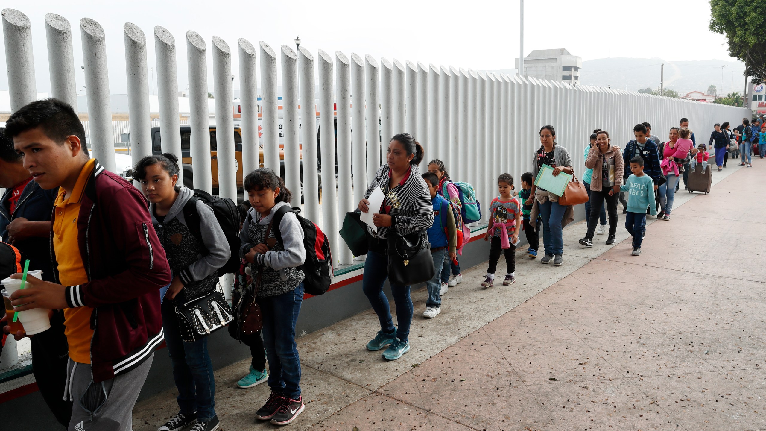 This July 26, 2018, file photo shows people lining up to cross into the United States to begin the process of applying for asylum near the San Ysidro port of entry in Tijuana, Mexico. (Gregory Bull / Associated Press)