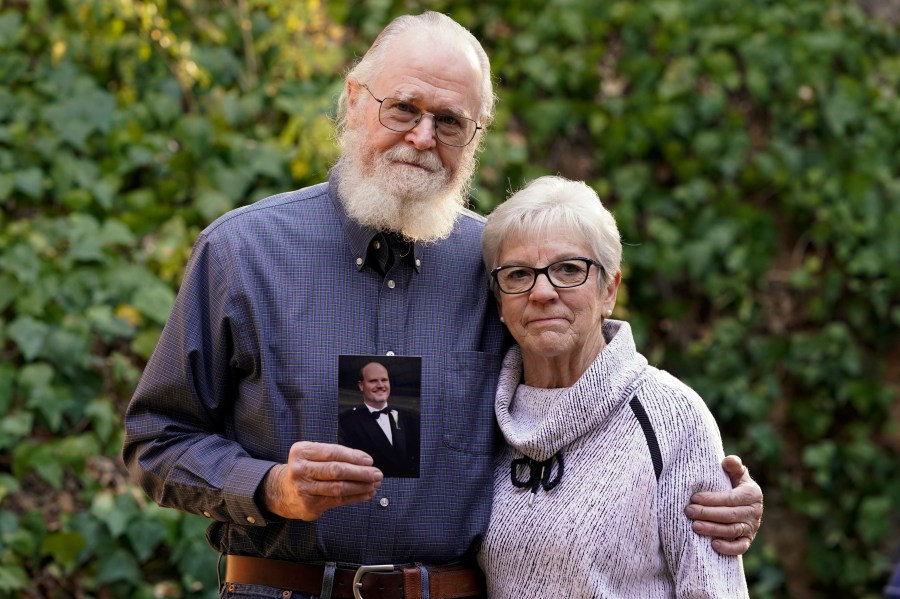 Clark McIlvain and Kathleen McIlvain hold a photo of their son, Charles McIlvain, at their home in Woodland Hills on Dec. 3, 2020. (Ashley Landis / Associated Press)