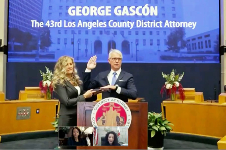 In this photo from the County of Los Angeles streaming video, incoming Los Angeles County District Attorney George Gascon is sworn in as his wife Fabiola Kramsky holds the Bible in downtown Los Angeles Monday, Dec. 7, 2020. (County of Los Angeles via AP)