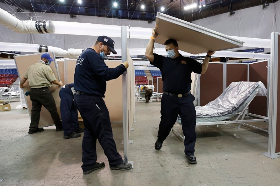 In this April 18, 2020, file photo, partitions are installed between beds as Sleep Train Arena is turned into a 400-bed emergency field hospital to help deal with the coronavirus, in Sacramento, Calif. Due to the recent spike in COVID-19 cases officials are rushing to reopen the former home of the NBA's Sacramento Kings, to patients. (AP Photo/Rich Pedroncelli, File)